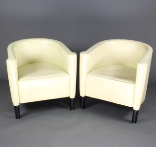 A pair of Art Deco style tub back armchairs upholstered in white leather and raised on ebonised supports 