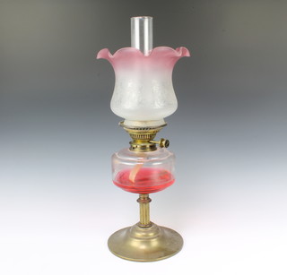 A Victorian oil lamp with clear glass reservoir, etched glass shade and clear glass chimney, raised on a gilt metal base 