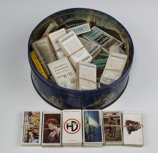 A circular biscuit tin containing a collection of Wills cigarette cards