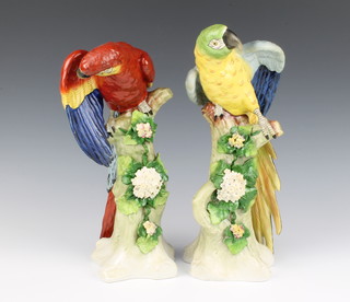 A pair of 20th Century German Sitzendorf porcelain figures of parrots on rocky floral encrusted tree stumps 32cm 