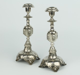 A pair of Continental repousse silver candlesticks with waisted stems decorated with masks on raised circular bases with scroll feet 586 grams 26cm 