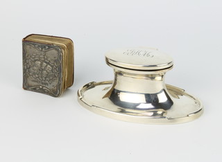 An oval silver capstan inkwell with chased monogram, Birmingham 1921, 12cm together with a silver mounted Reynolds angels prayer book 