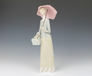 A Lladro figure of a lady standing, holding a parcel and a parasol 36cm  
