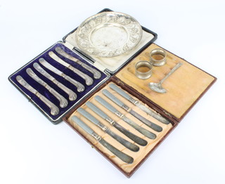 A cased set of 6 silver handled butter knives with pistol butt grips, 2 silver napkin rings and 2 other items