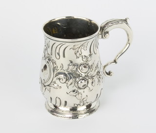 A Georgian Irish repousse silver mug with floral and scroll decoration and S scroll handle, 300 grams, with later presentation inscription 