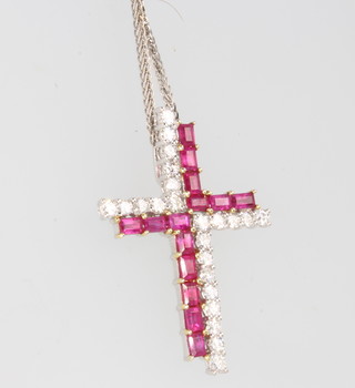 An 18ct white gold ruby and diamond set cross on a do. chain 