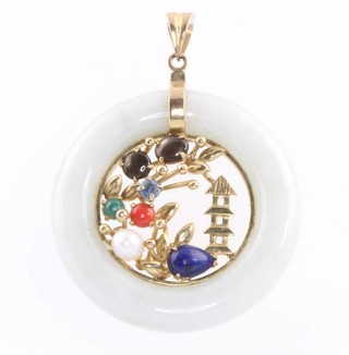 A 14ct yellow gold hardstone mounted Chinese circular pendant with pagoda and flowers 