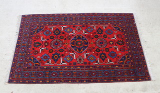 A red and blue ground Caucasian rug with medallion to the centre supported by 2 further medallions within a multi row border 240cm x 152cm 