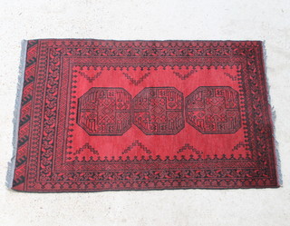 A red and black ground Afghan rug with 2 octagons to the centre 155cm x 99cm 
