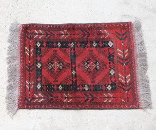 A red and black ground Afghan rug with 2 diamond medallions to the centre within a multi-row border 111cm x 83cm 