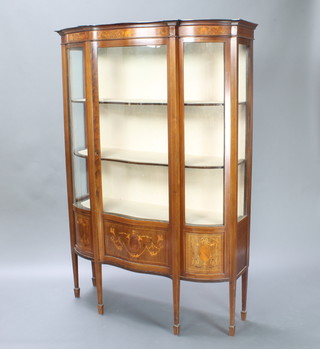 An Edwardian inlaid mahogany display cabinet of serpentine outline, fitted shelves enclosed by glazed panelled doors raised on square tapering supports ending in spade feet 177cm h x 124cm w x 42cm d 