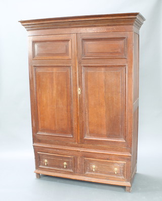 An 18th/19th Century oak press cabinet/wardrobe with moulded cornice enclosed by a panelled door, the base fitted 2 drawers with brass drop handles 190cm h x 136cm w x 59cm d 