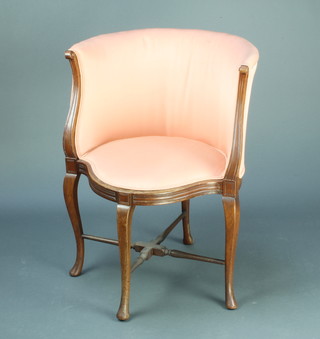 An Edwardian tub back armchair upholstered in pink material raised on cabriole supports with X framed stretcher 