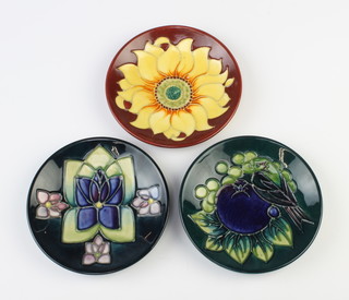 Three modern Moorcroft dishes, 1 with red ground decorated a sunflower, 1 green ground decorated with a bird amongst fruit and 1 blue ground decorated with stylised flowers 12cm 