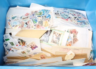 A blue crate of various loose used world stamps 