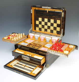 Of Royal Interest, Drew & Sons, an Edwardian coromandel and chrome mounted games compendium, the hinged lid inlaid Edward VII Royal Cypher and with countersunk handles 26cm h x 42cm w, the interior fitted a coromandel and inlaid ivory chess/backgammon board with chrome hinges.   The upper tray fitted a red and white carved ivory chess set, together with a red and white carved ivory domino set, 4 circular score indicators, 12 red ivory peg markers all contained within a satinwood tray and also together with 5 later associated packs of De La Rue playing cards.   The satinwood lift out trays fitted 2 large bezique markers (1f), 2 small associated bezique markers the base marked The Camden Tom Thumb Whist Marker and 4 later associated De La Rue  packs of  playing cards.  The drawer fitted  7 sections (1 receptacle vacant) containing  pair of ivory dice shakers, 5 carved ivory dice, 43 blue circular composition counters (1 counter f), 45 ditto purple, 42 ditto white and 2 associated sets of playing cards.  The divided base section fitted a circular satinwood roulette wheel with 3 metal figures of horses and jockeys, 6 later plastic figures of horses, 28 ivory jack straws.  The fall front fitted a pair of ivory and chrome cribbage boards with 2 ivory score markers (both with loose hands). 
