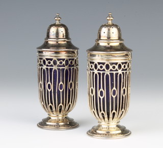 A pair of silver pierced urn shaped pepperettes with blue glass liners Birmingham 1911, 144 grams 