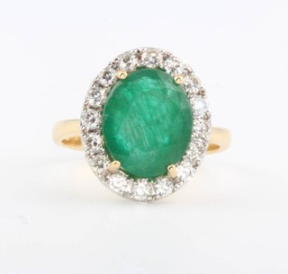 An 18ct yellow gold oval emerald and diamond cluster ring, the centre stone approx. 4.26ct surrounded by brilliant cut diamonds approx. 0.6ct size M