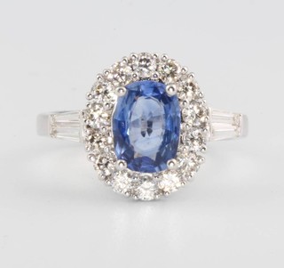 An 18ct white gold oval sapphire and diamond cluster ring, the centre stone approx. 1.47ct, surrounded by brilliant cut diamonds and tapered baguettes to the shoulders approx. 0.75ct, size L 