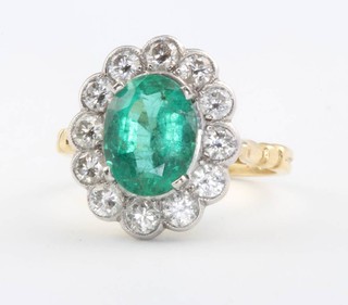 An 18ct yellow gold oval emerald and diamond cocktail ring, the oval cut centre stone surrounded by 12 brilliant cut diamonds size M 1/2 