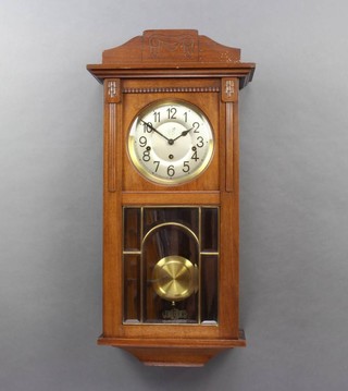A Continental striking wall clock with silvered dial and Arabic numerals contained in a carved walnut case 