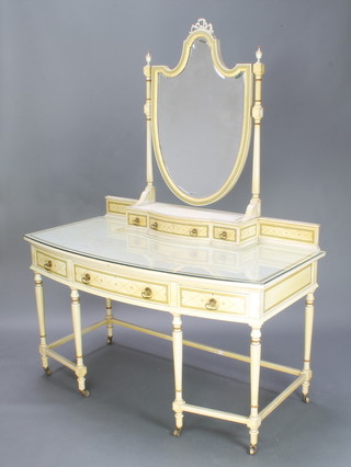 An Edwardian Sheraton style white and cream painted bow front dressing table with raised back and shield shaped bevelled plate mirror, the base fitted 1 long drawer flanked by 2 short drawers, raised on 6 turned and fluted supports with box framed stretcher 138cm h x 69cm h 