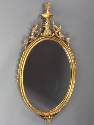 A Georgian style oval plate wall mirror contained in a decorative gilt frame surmounted by a lidded urn 98cm x 55cm 