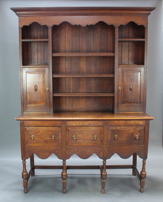 An Edwardian 17th Century style oak dresser, the raised back with moulded cornice and fitted shelves above cupboards, 1 fitted a drawer and racking, the other fitted 6 long drawers, the base fitted 3 long drawers raised on turned and block supports with box framed stretcher 214cm h x 63cm w x 53cm d 