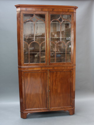 A Georgian mahogany double corner cabinet, the upper section with moulded cornice, fitted shelves enclosed by astragal glazed panelled doors, the base fitted a cupboard enclosed by panelled doors, raised on bracket feet 219cm h x 120cm w x 59cm d