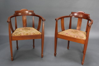 A pair of Edwardian Art Nouveau inlaid mahogany tub back chairs with upholstered drop in seats, raised on square tapered supports ending in spade feet 