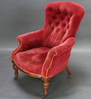 A Victorian armchair upholstered in red buttoned material raised on turned supports 