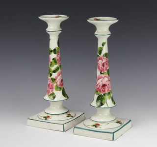 A pair of Wemyss tapered candlesticks on square bases decorated with roses, painted and impressed marks, 30cm.  Retailed by T Goode & Co 