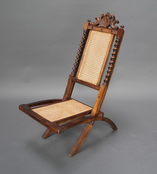A Victorian carved walnut folding chair with woven cane seat and back 