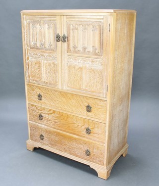 A 1930's Heals style carved limed oak tallboy with linen fold panelled doors, the base fitted 3 long drawers, raised on bracket feet 53cm h x 84cm w x 47cm d 