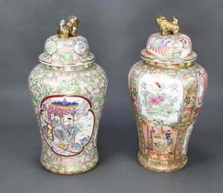 Two large 20th Century famille rose style baluster vases and covers with lion finials and panels of figures and birds 86cm h 