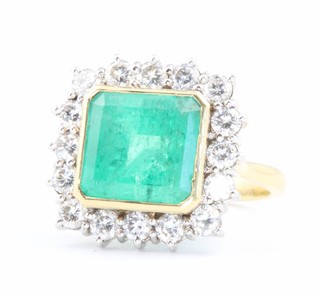 An 18ct yellow gold emerald and diamond cluster ring the square cut centre stone approx. 6ct surrounded by brilliant cut diamonds 1.6ct size L, together with an EDR certificate 