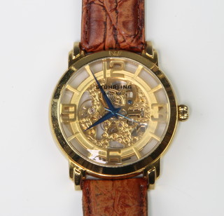 A Stuhrling gentleman's gilt wristwatch with visible movement on a leather strap, in original box 