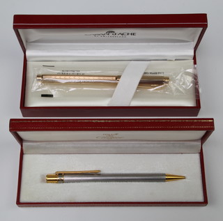 A Cartier steel and gold plated ball pen boxed and a Caran d'Ache gold plated do. 