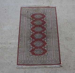 A pink and white ground Persian style rug with 6 medallions to the centre within a multi row border, slight staining 158cm x 96cm 
