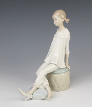 A Lladro figure of a girl sitting on a pouffe 20cm 