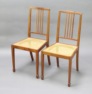 A pair of Edwardian mahogany stick and rail back bedroom chairs with woven cane seats, raised on square tapered supports, spade feet