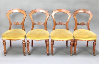 A set of Victorian carved mahogany hoop back dining chairs with carved mid rails and seats of serpentine outline, raised on turned supports 