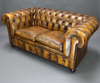 A 2 seat Chesterfield upholstered in brown buttoned leather, raised on bun feet 74cm h x 160cm w x 90cm d 