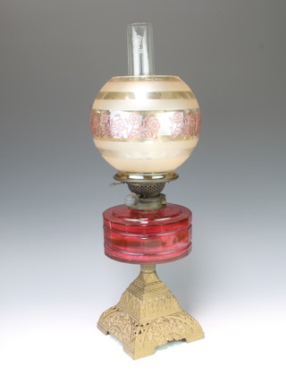 A Victorian cranberry glass oil lamp reservoir raised on a pierced gilt framed iron base and with Hinks's fittings, complete with chimney and an associated clear clear glass shade 58cm h x 15cm 
