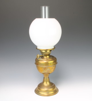 A brass oil lamp with clear glass chimney and opaque glass shade 