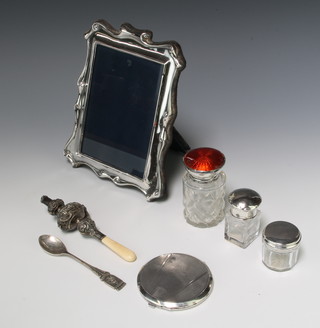 An Edwardian repousse silver teether rattle whistle Birmingham 1904 13cm,  3 silver mounted toilet jars, a photograph frame Sheffield 1986, a compact and a spoon