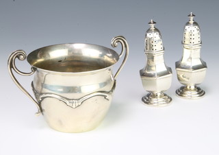 A pair of Victorian silver hexagonal peppers Chester 1894, 9cm, 68 grams and an Edwardian repousse silver two handled sugar bowl 172 grams 