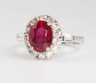 An 18ct white gold oval single stone ruby and diamond cluster ring, the treated centre stone 2.42ct surrounded by brilliant cut diamonds with baguette cut shoulders 0.66ct size L 
