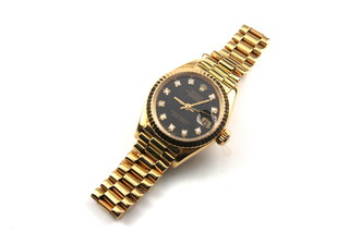 A lady's 18ct yellow gold Rolex Oyster Perpetual Date Just Automatic Chronometer wrist watch with 26 mm case black dial and diamond dot hour markers on a President bracelet stamped 8570F boxed and with original outer box