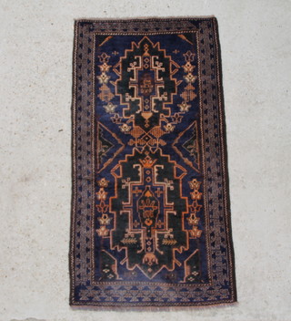 A blue and brown ground Baluchi rug with 2 medallions to the centre within a multi-row border, some wear 156cm x 80cm 
